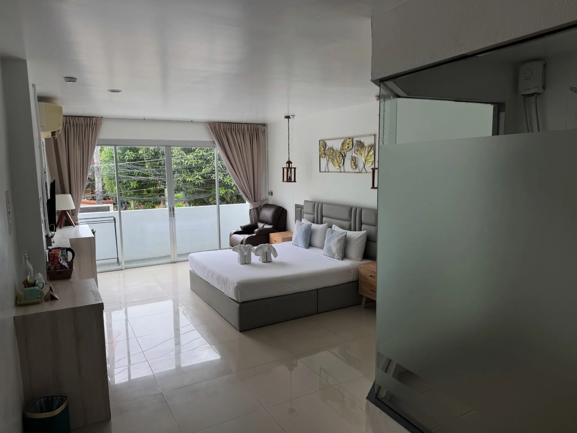 Double room with a large bed, a wooden desk and a balcony door onto greenery