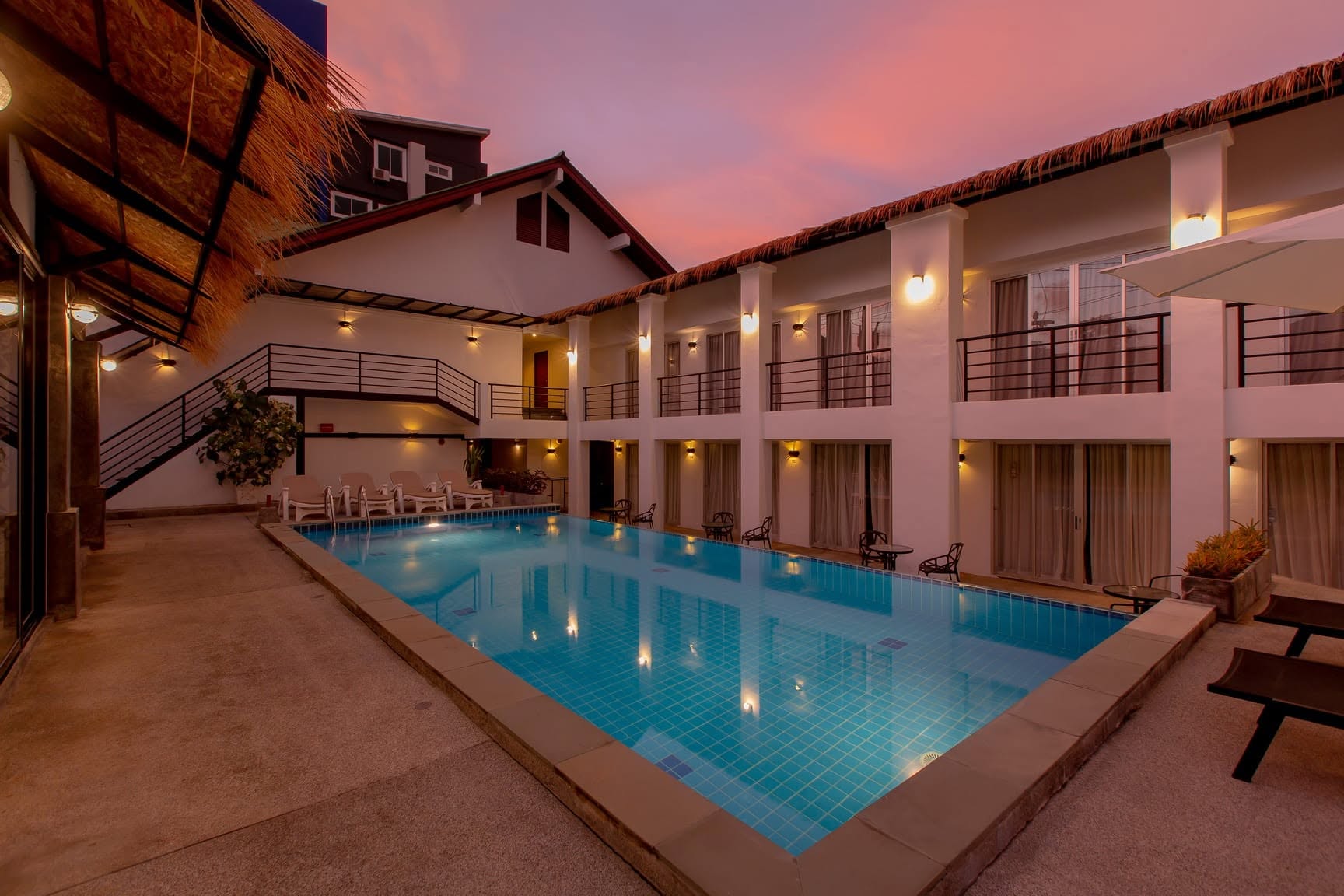 Courtyard pool at sunset with loungers and the poolside bar
